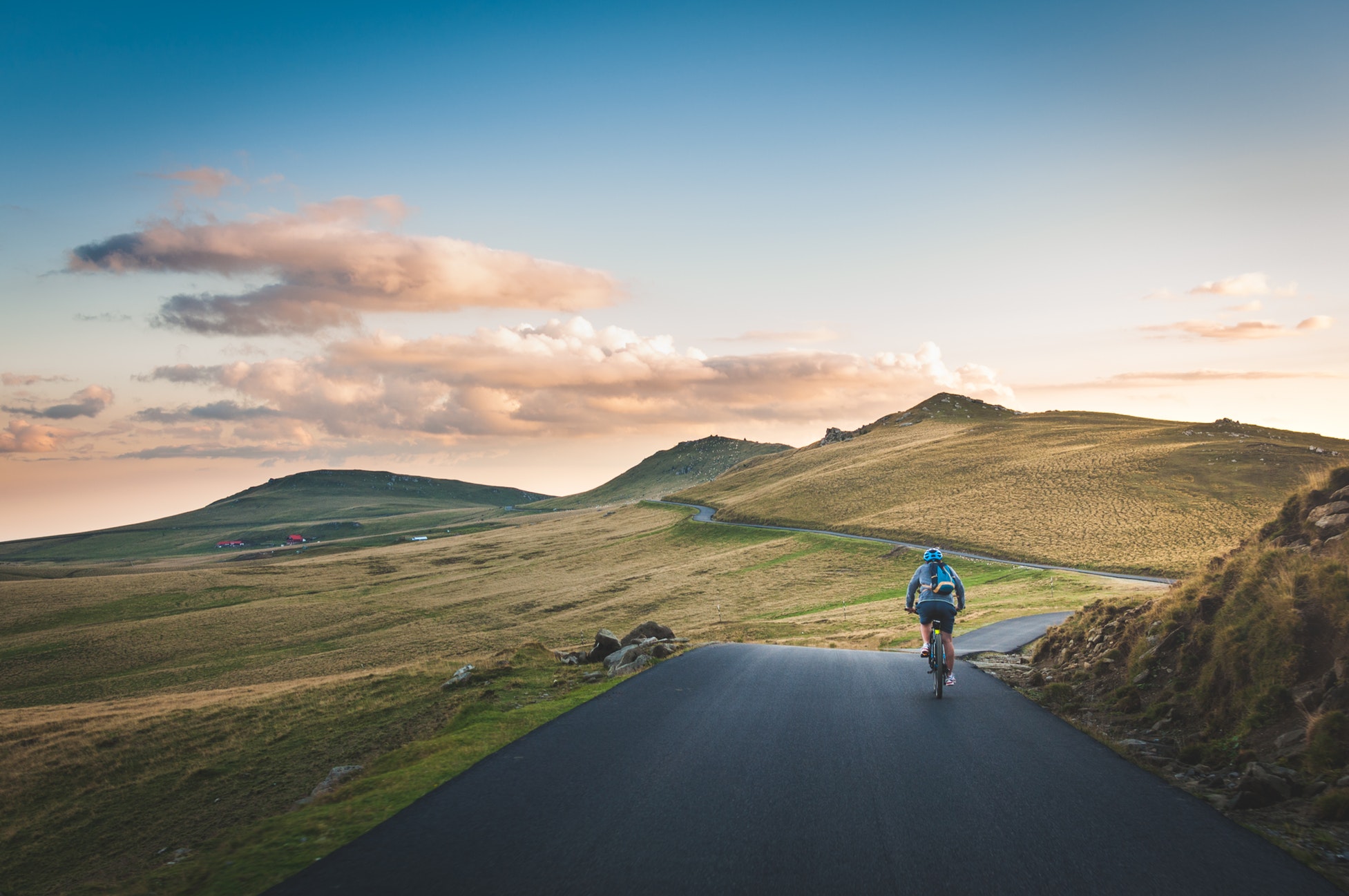 Man cycling towards green hills