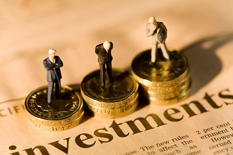Three small figures standing on stacks of coins