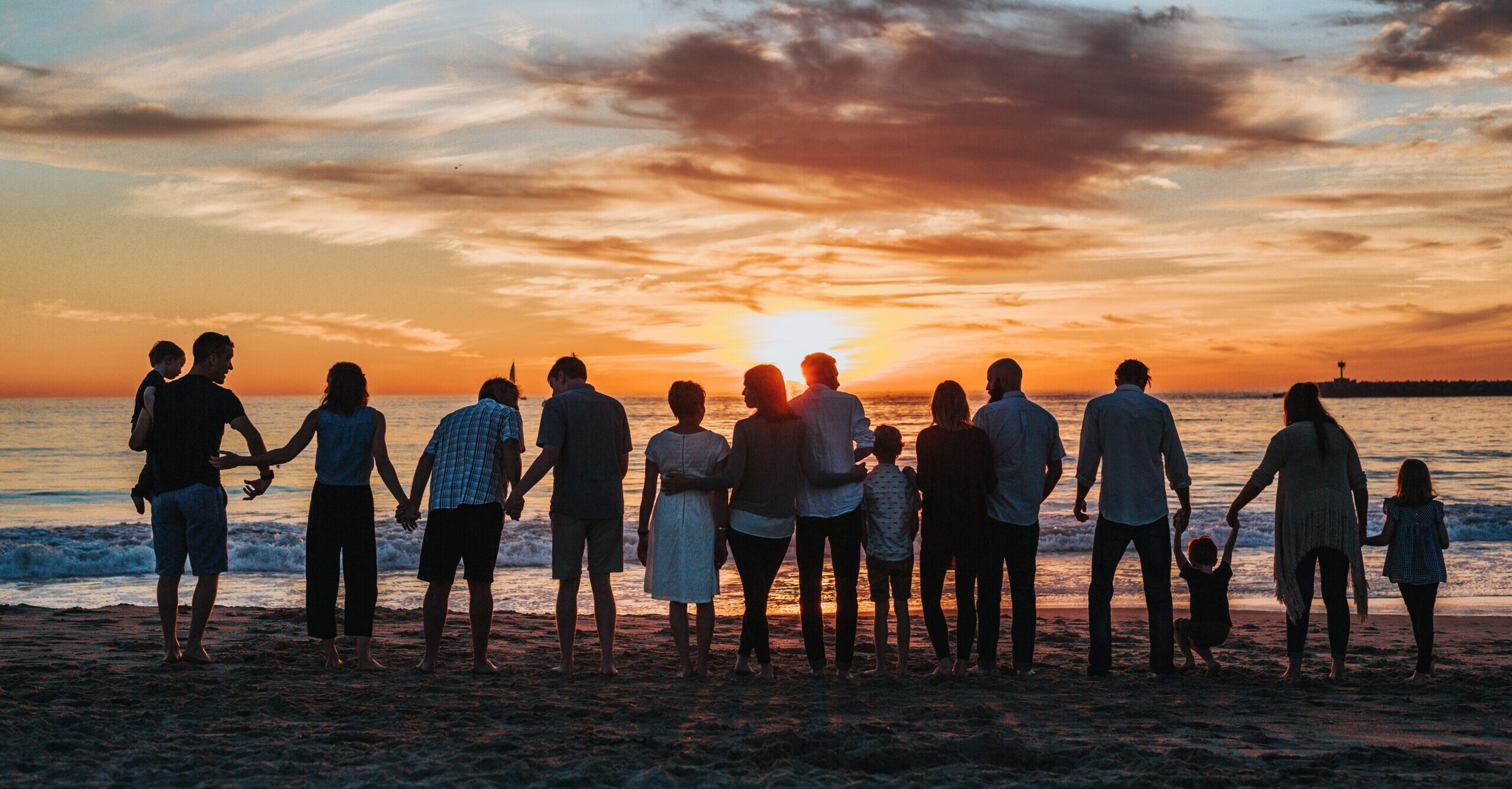 People holding hands on a beach during sunset