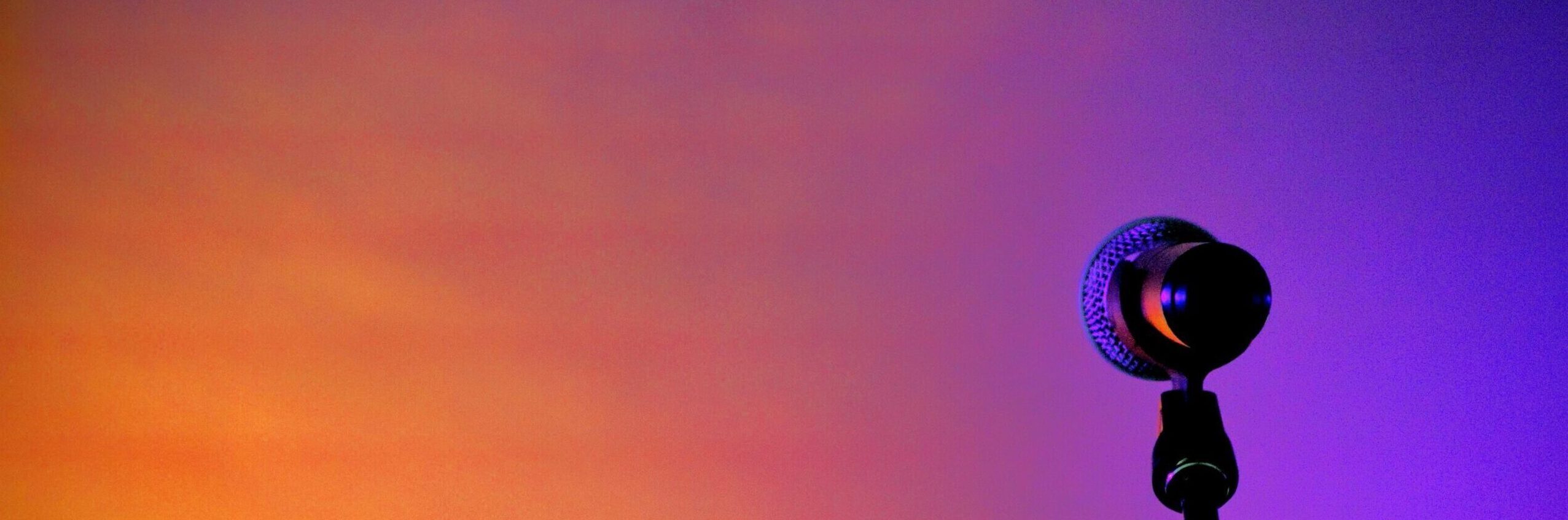Microphone standing against a two-tone orange and purple background.